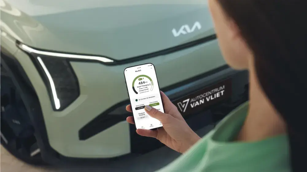 Kia-rijder kijkt op telefoon naar de Kia Smart Charge app, naast een Kia EV3